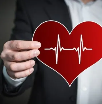 Muž drží papierové srdce s krivkou EKG